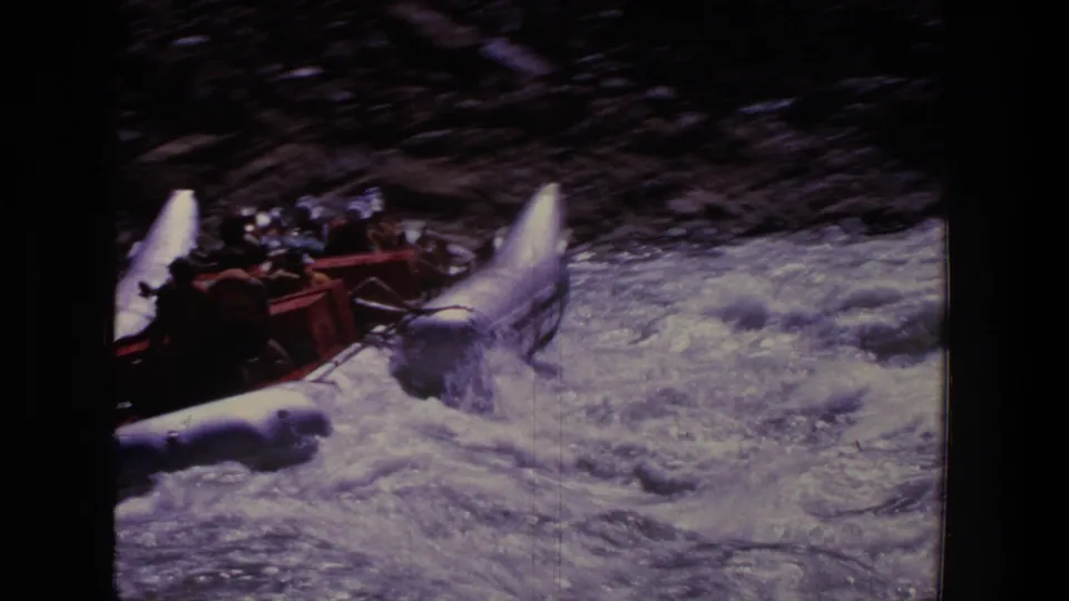 A crowded inflatable raft pushes through churning Utah whitewater, with passengers gripping the raft in a grainy 1969 frame.