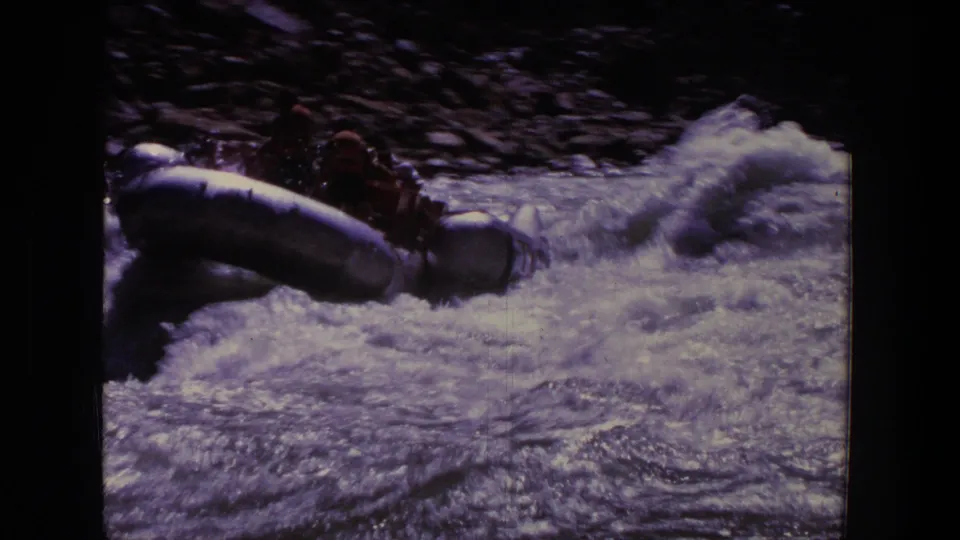 1969 Utah 8mm frame showing a rubber raft with passengers moving into churning whitewater rapids.