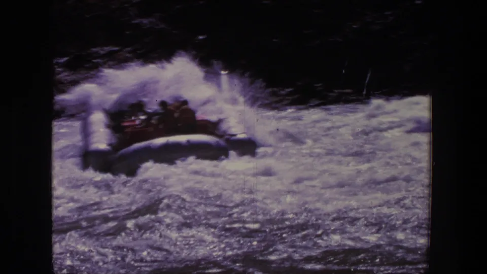 Rubber raft carrying several people bounces through whitewater in the Utah home-movie footage.