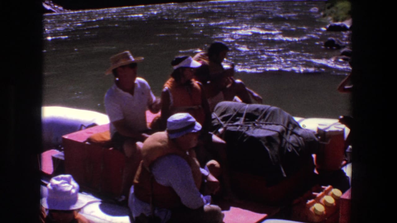 1969 Utah rafting passengers sit among gear in a white inflatable raft on sunlit river water.