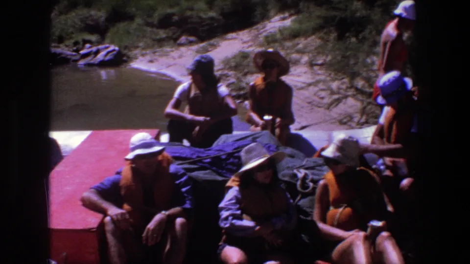 1969 Utah 8mm frame showing raft passengers in life vests clustered around gear near the riverbank.