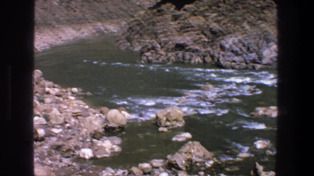 1969 Utah 8mm frame showing a rocky canyon river with small rapids, dry slopes, and dark film borders.