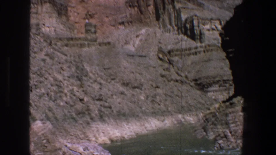 1969 Utah 8mm frame showing a narrow river section below dry, layered canyon rock and dark border artifacts.