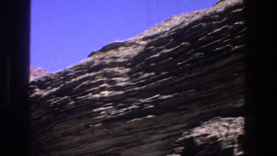 1969 Utah home-movie view of a sloped, striated canyon wall passing behind dark foreground framing.