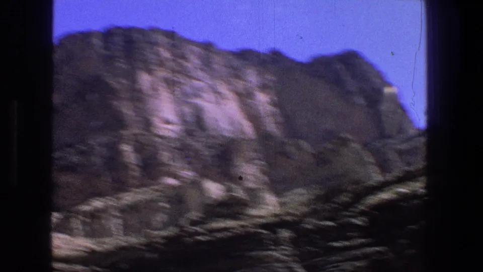 Handheld 1969 Utah home-movie frame with a rocky cliff face, blue sky, and motion blur from the camera move.
