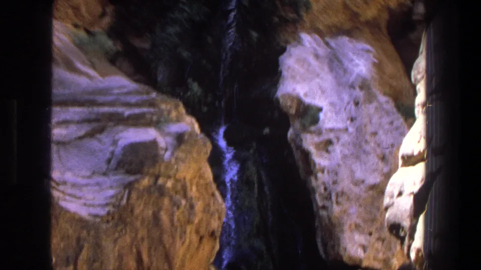 1969 Utah 8mm frame looking downward into eroded canyon rock with a narrow dark channel where water appears to pass.