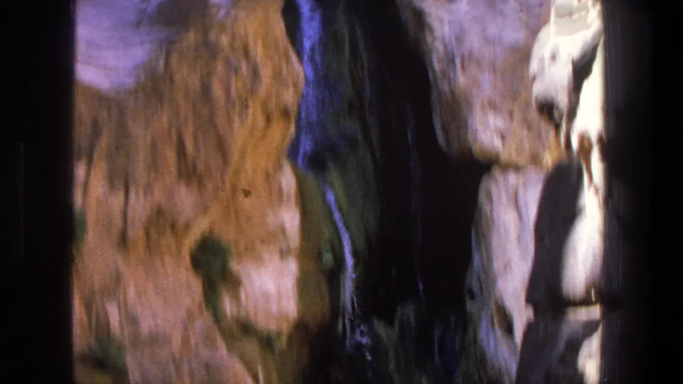 Handheld 1969 Utah frame showing blurred canyon rock surfaces and a narrow dark gap where water moves between stones.