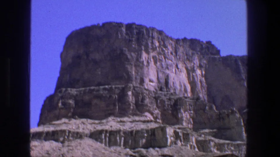 A high Utah canyon formation rises against blue sky in the supplied 1969 8mm footage.