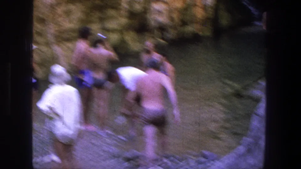 People in 1960s swimwear wade and gather near a shaded creek pool in metadata-supported Utah footage.