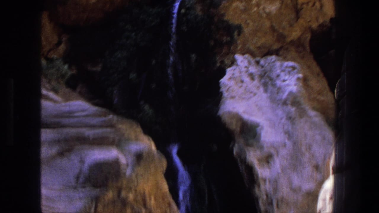 1969 Utah 8mm frame with pale canyon stone, dark crevices, and water falling through the rocks.
