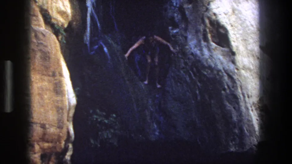 A swimmer moves through dark water beside textured canyon rock in this 1969 Utah home-movie frame.