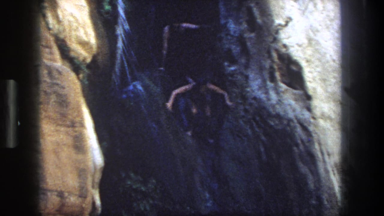 1969 Utah 8mm frame showing a man poised on a canyon rock ledge above dark water.