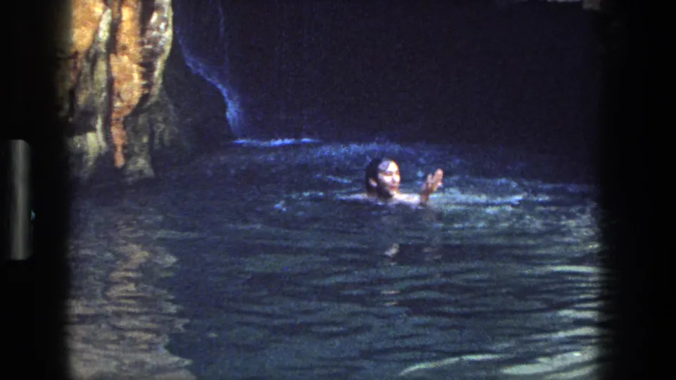 1969 Utah 8mm frame showing a woman bathing or swimming in a shadowed canyon pool.