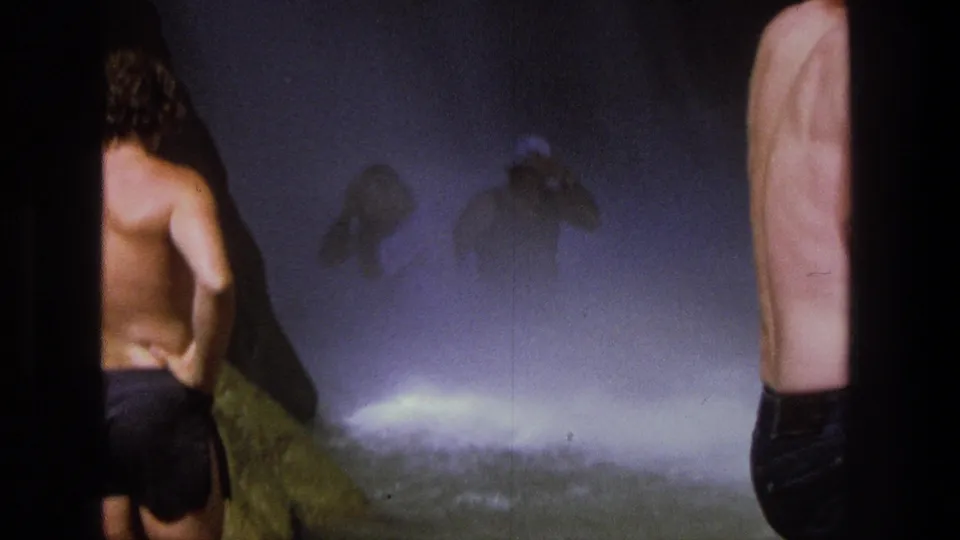 Home-movie frame from Utah in 1969 showing a man in swim trunks near a misty cascade, partly framed by film edges.