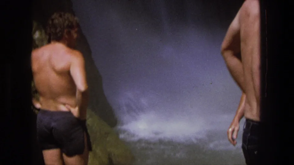 1969 Utah 8mm frame with partially cropped men in swim trunks near churning spray at a waterfall.
