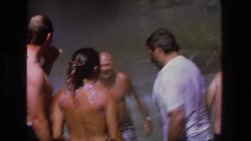 A candid 1969 Utah frame shows adults gathered in water below a waterfall, with mist softening the background.