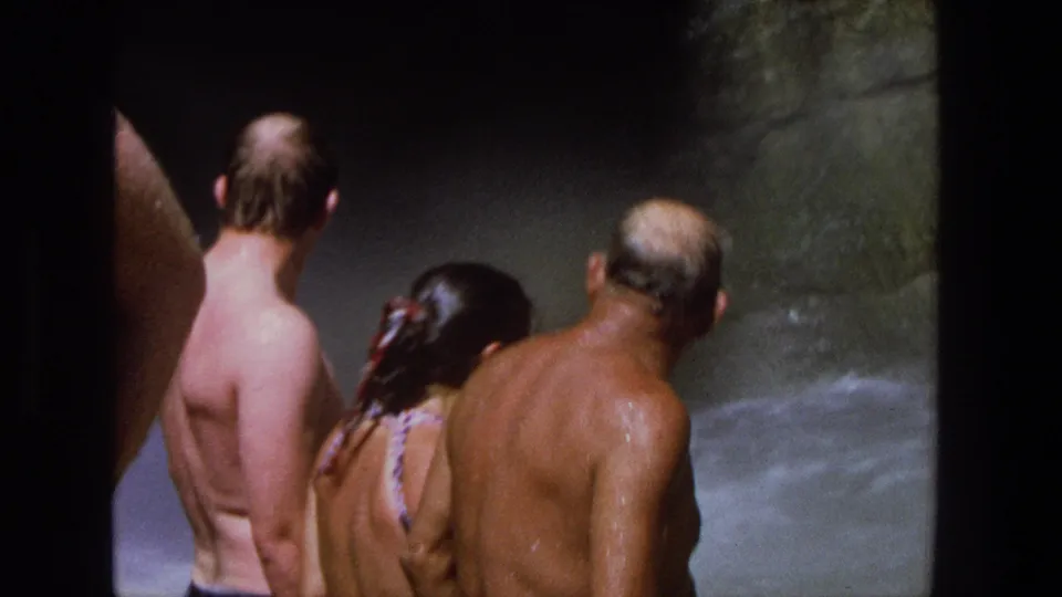 1969 Utah home-movie frame showing people in swimwear near churning water and waterfall spray.