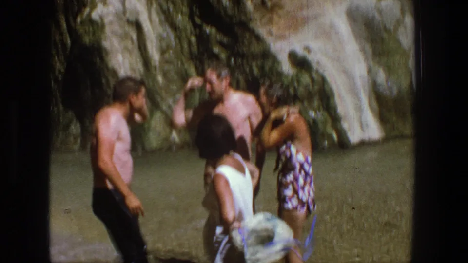 Adults appear to laugh and adjust clothing near a Utah waterfall in a late-1960s vacation scene.