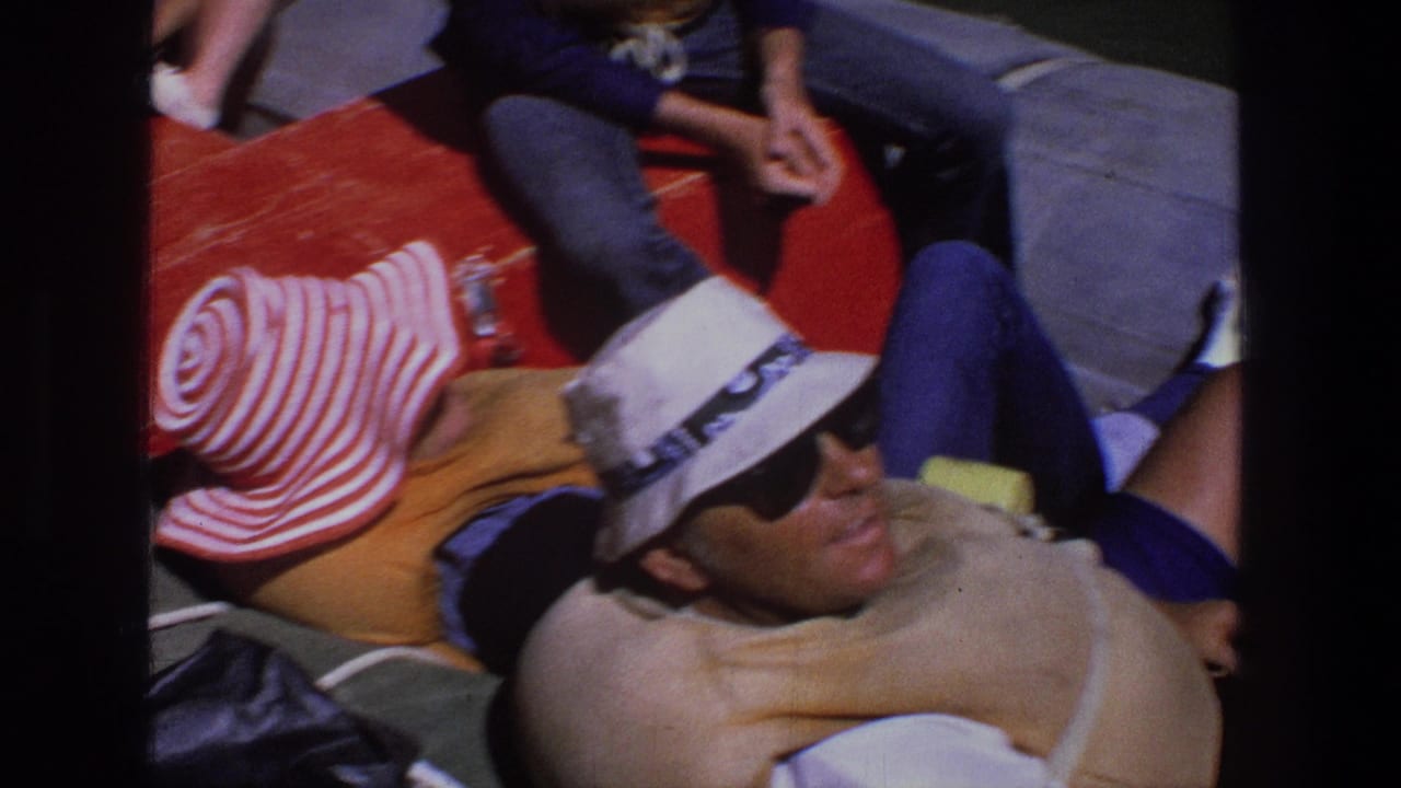 Man in a white hat reclines beside others on a red cushioned boat surface.