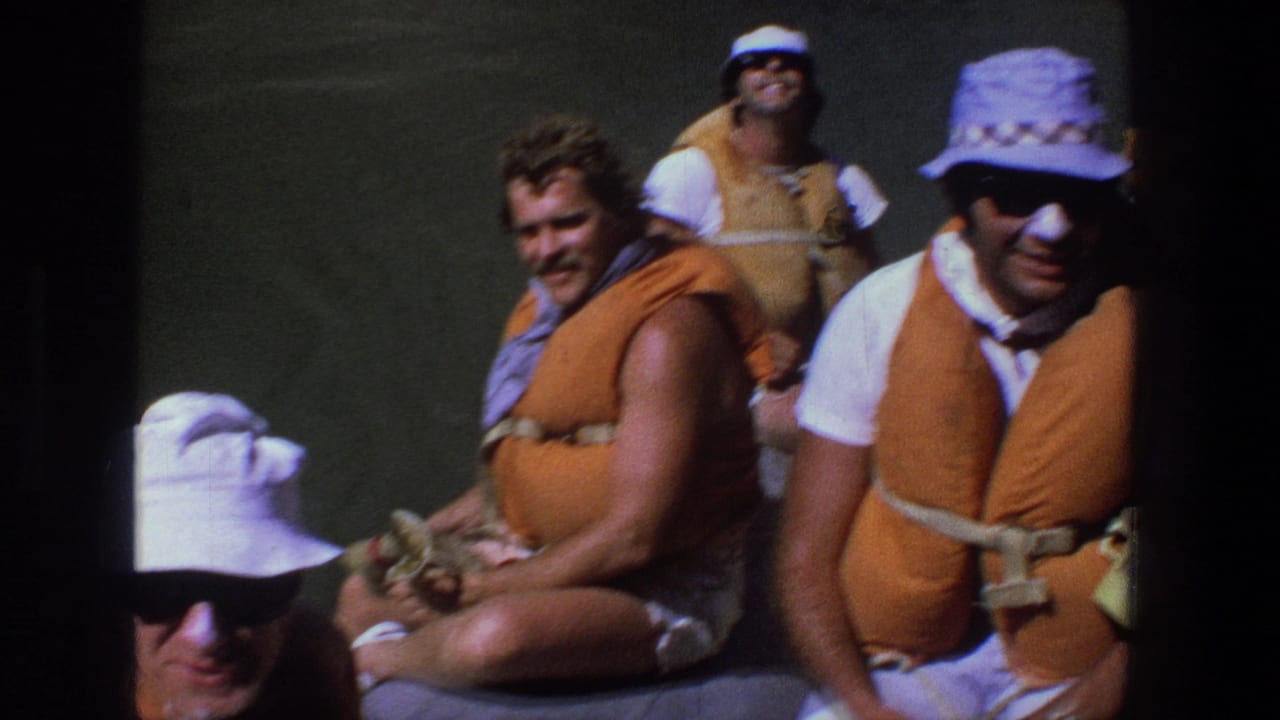 Several adults in life vests sit close together on a raft or boat.