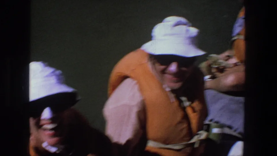 Close Super 8 view of adults in life vests on a 1969 Utah river outing, with strong sun and shadow across faces.