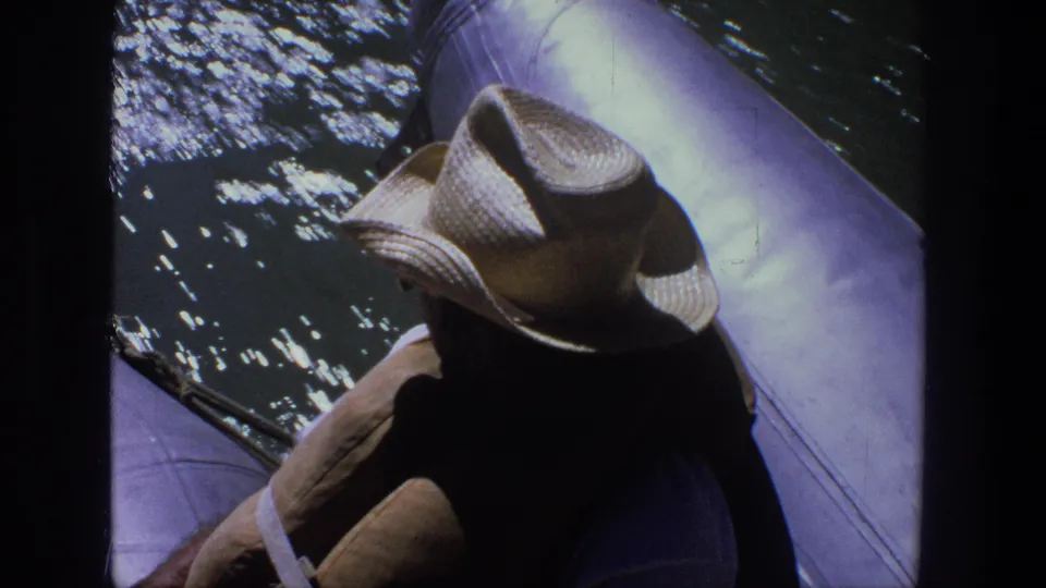 High-angle 8mm view of the Utah boat passenger's straw hat and shoulders beside rippling lake water.