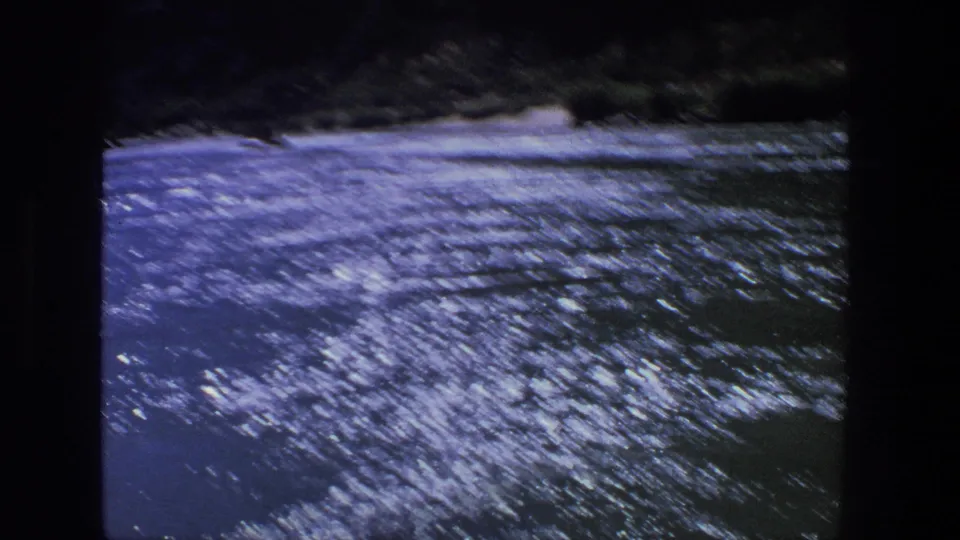 1969 Utah lake view from the boat, showing shimmering water and a dark distant shoreline.