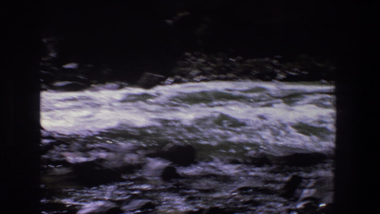 Fast river current and white foam crossing a rocky channel.