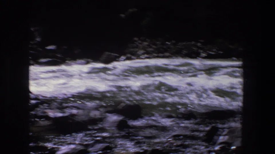 1969 Utah home-movie frame showing turbulent river water and foam over rocks, viewed from a fixed riverside position.