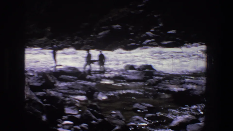 1969 Utah 8mm frame with distant silhouetted people standing on rocks beside bright whitewater in a canyon setting.