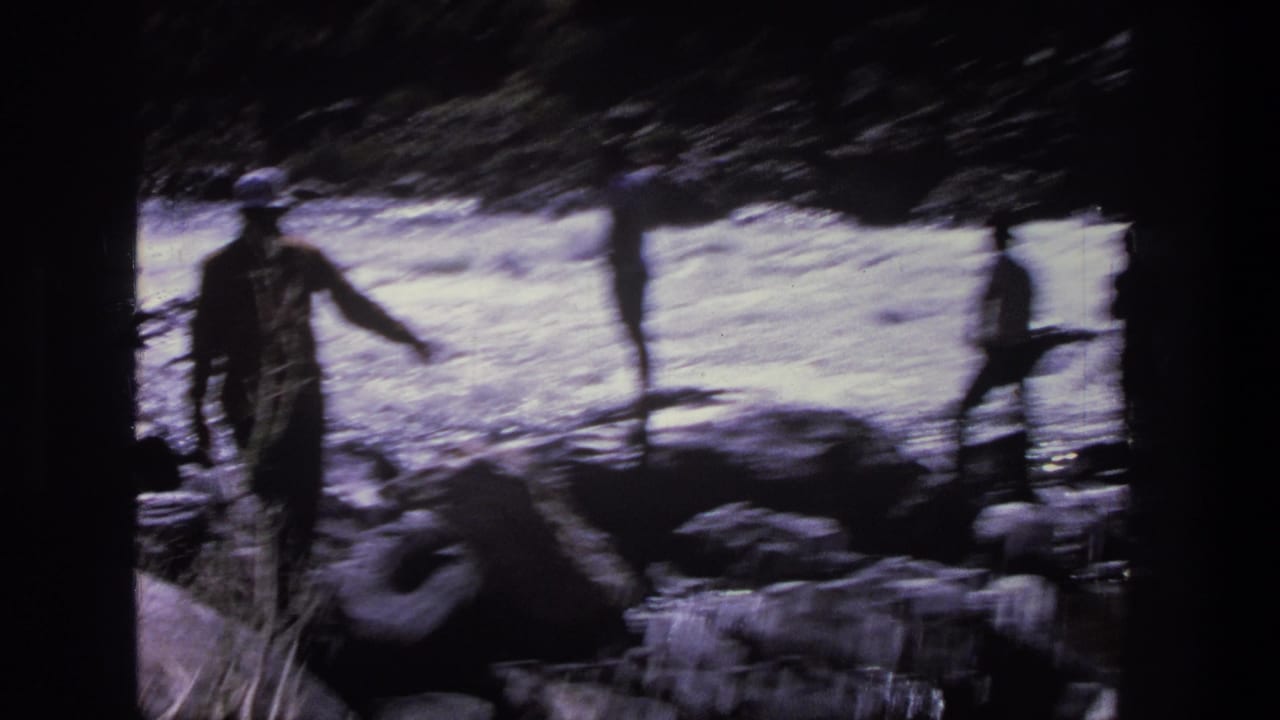 1969 Utah home-movie frame with a dark figure near rocky streamside terrain and bright water in the background.