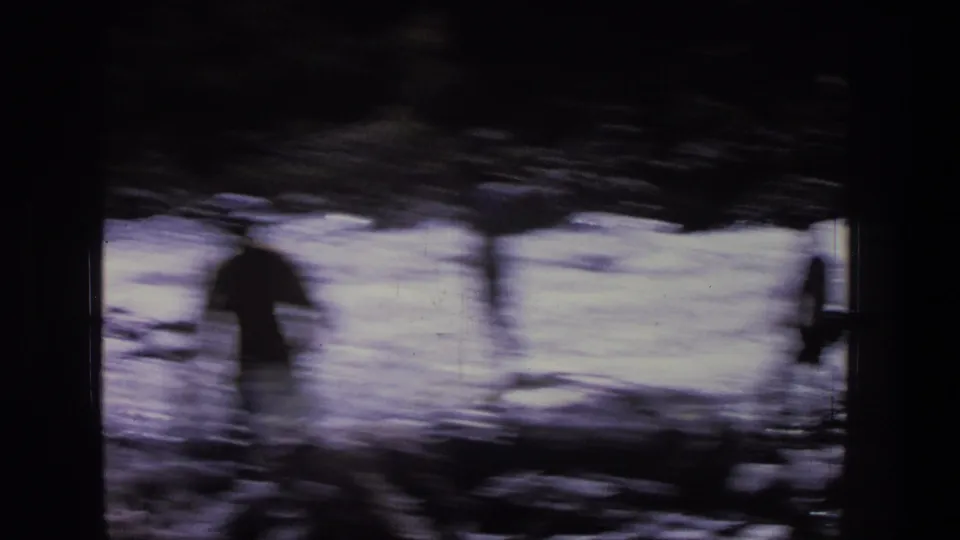 Motion-blurred 8mm frame of people moving along a Utah riverbank, with water and rocks visible through heavy shadow.