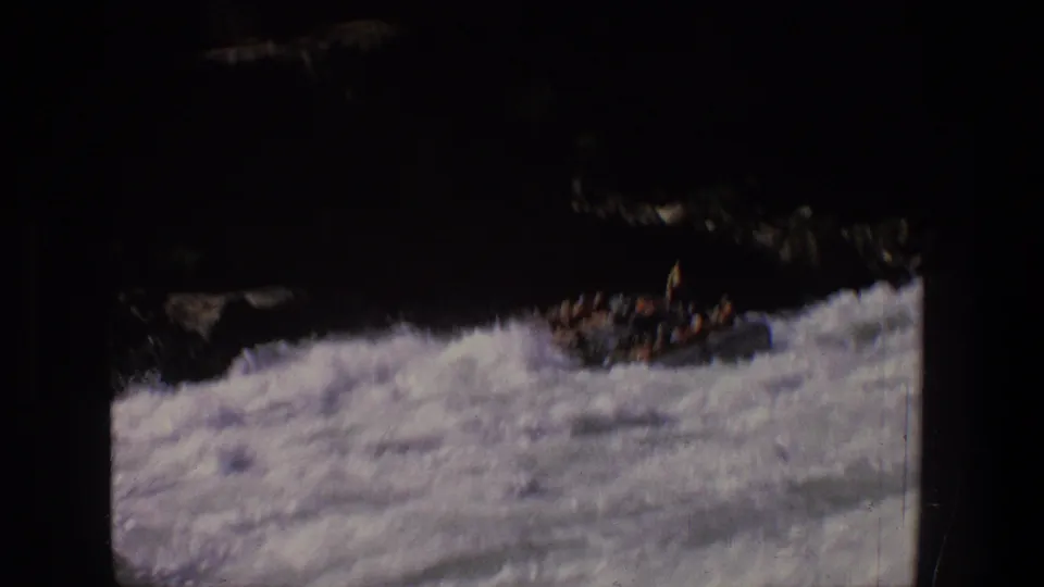 1969 Utah 8mm frame with the raft mostly obscured by foaming rapids, leaving only riders and boat edges visible near the upper river line.