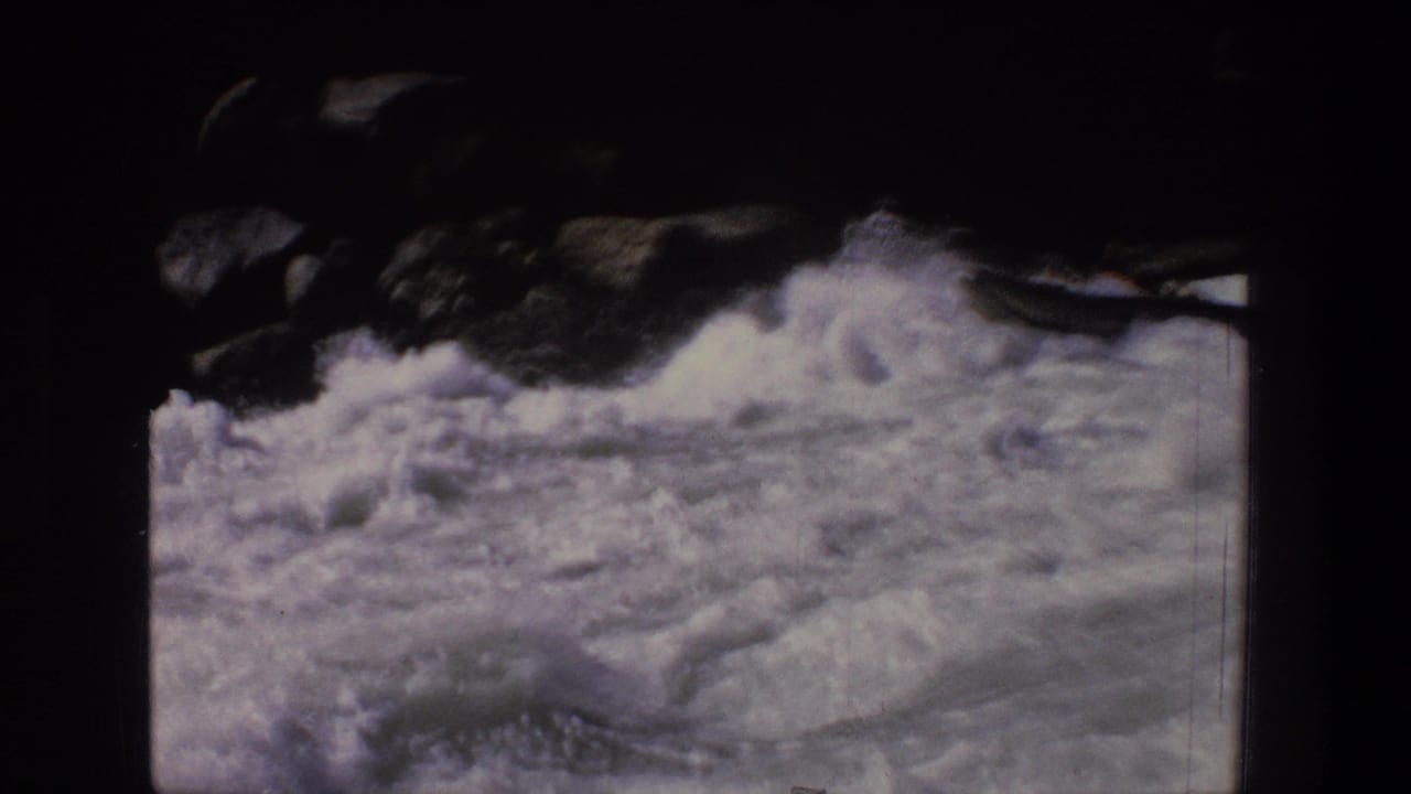 1969 Utah home-movie frame showing turbulent white water and dark rocky edges before the raft enters view.