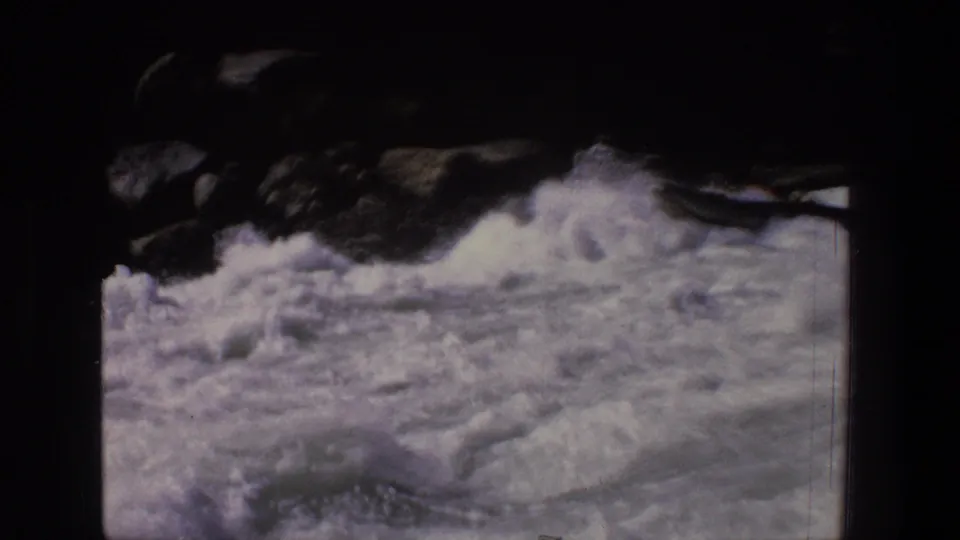 1969 Utah home-movie frame showing turbulent white water and dark rocky edges before the raft enters view.