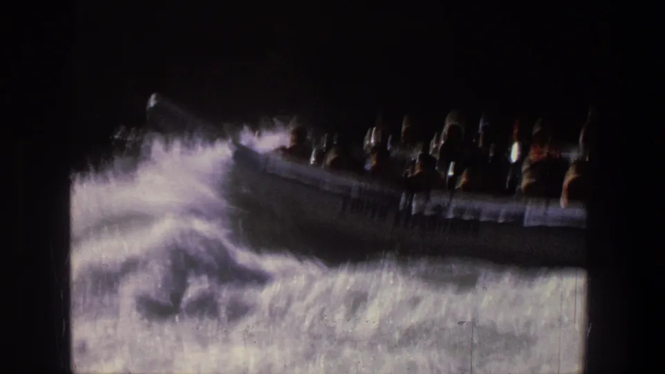 A silver inflatable raft carrying visible passengers cuts across foaming rapids in this 1969 Utah home movie frame.