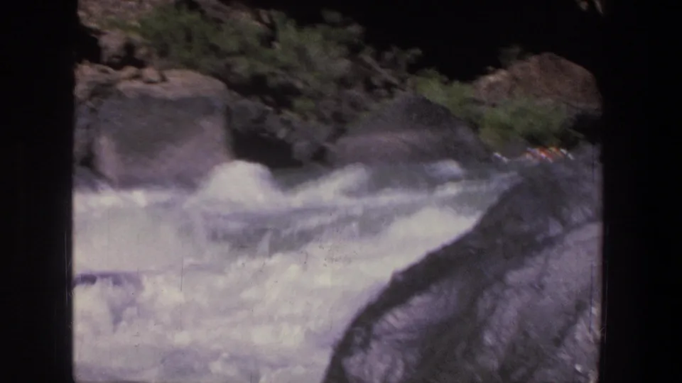 1969 Utah 8mm view of rushing whitewater near large dark boulders, sparse vegetation, and rocky canyon terrain.