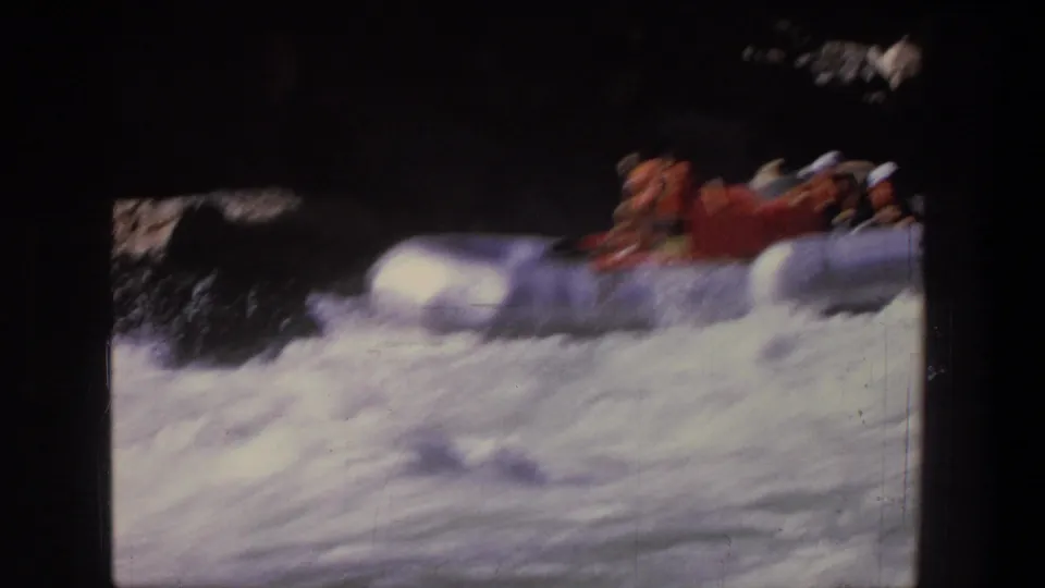 1969 Utah 8mm frame showing a red raft and seated rafters blurred by motion as they pass through foamy rapids.