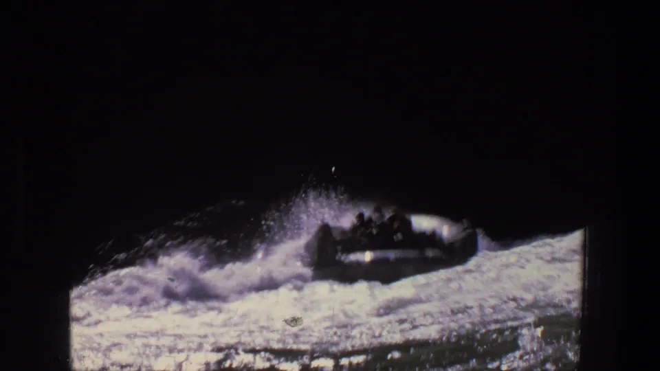 Inflatable raft in turbulent Utah river water, seen in a dark 8mm frame with occupants silhouetted against spray.