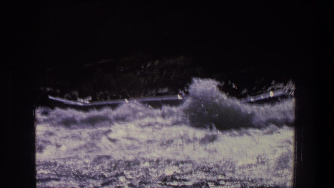 Vintage 8mm frame from Utah showing turbulent rapids and a high burst of spray near a canoe or small boat.