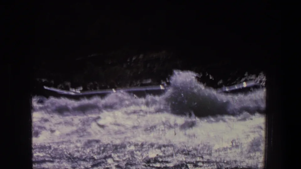 Vintage 8mm frame from Utah showing turbulent rapids and a high burst of spray near a canoe or small boat.