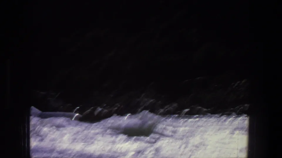 1969 Utah 8mm frame showing a small raft in foamy river rapids with dark banks and strong sun glare.