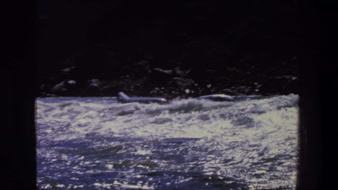 Foamy river current with a small raft near the upper edge of the frame.