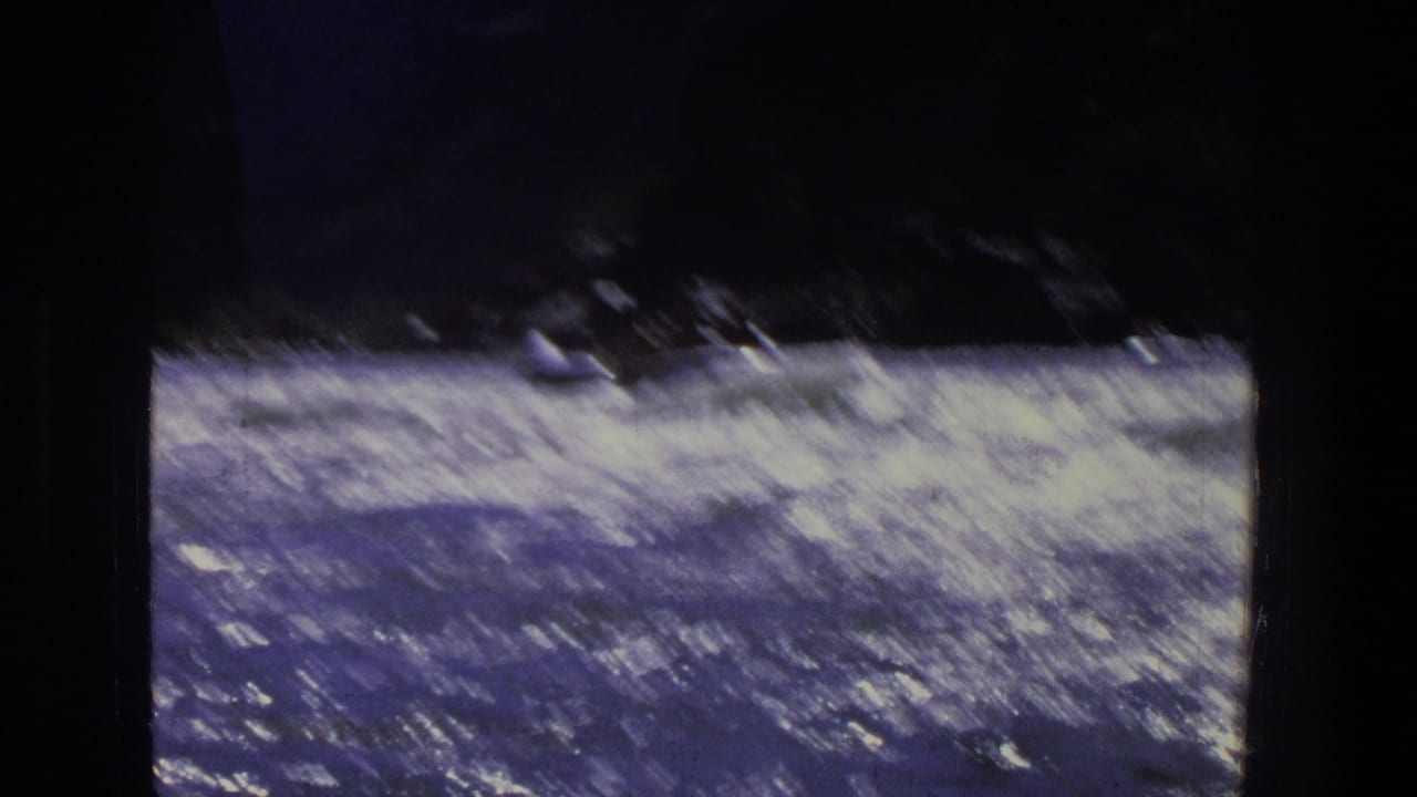 White-water river current beside dark canyon rock, framed by 8mm film borders.