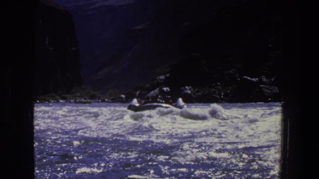 1969 Utah 8mm view of a small open boat moving through rough water below shadowed canyon rock.