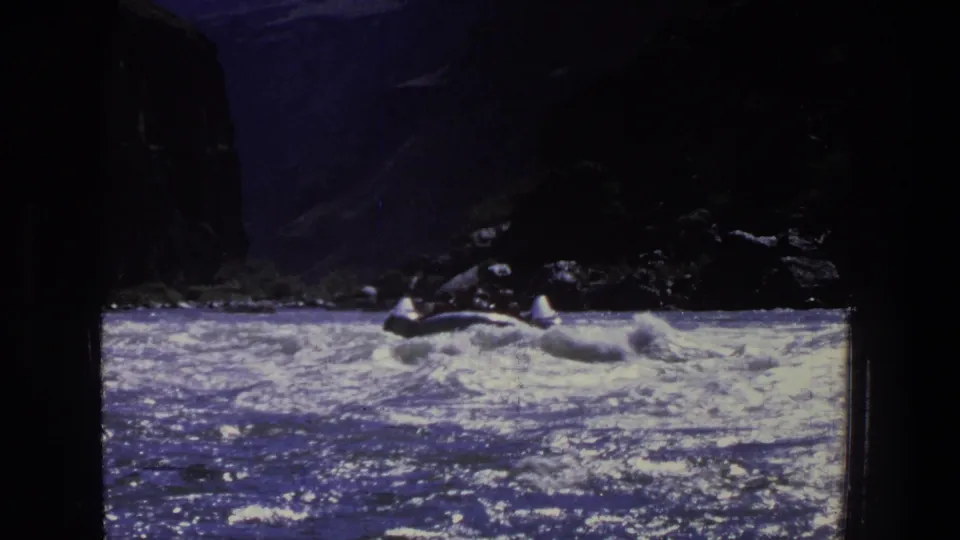 1969 Utah 8mm view of a small open boat moving through rough water below shadowed canyon rock.