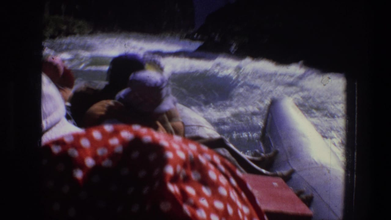 1969 Utah rafting footage frame with hat-wearing passengers near turbulent whitewater and shadowed canyon walls.