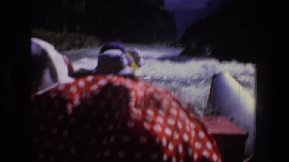 Soft 8mm frame from Utah in 1969 showing rafters and rapids, with red patterned fabric dominating the foreground.