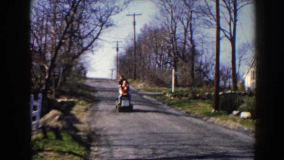 Near the end of the clip, the red-sweatered rider approaches on the Pequot Lakes road under bright daylight and bare roadside trees.