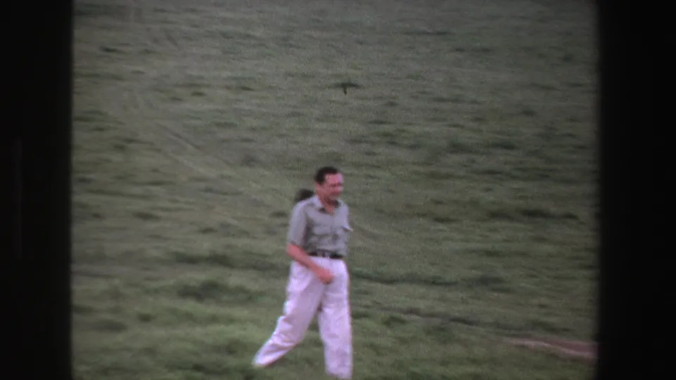 Near the end of the 1969 South Africa clip, the man walks across green grass beside faint field tracks, with wildlife less prominent.